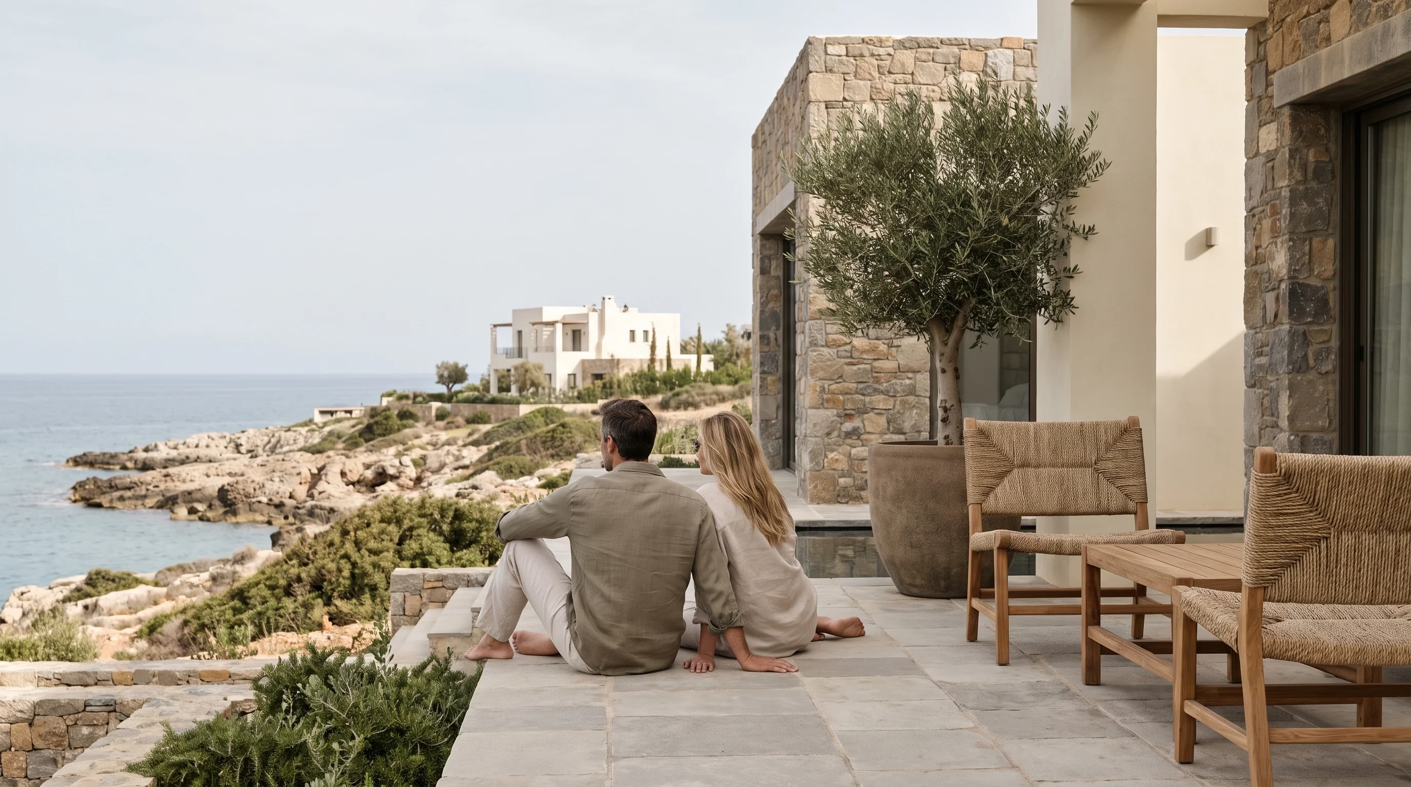 Two people seated on a terrace overlooking the coast